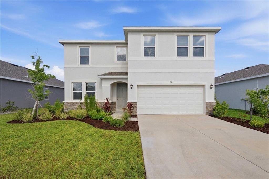 A two-story house with a light-colored stucco exterior, stone accents, and a two-car garage — 624 160TH STREET E, BRADENTON, FL