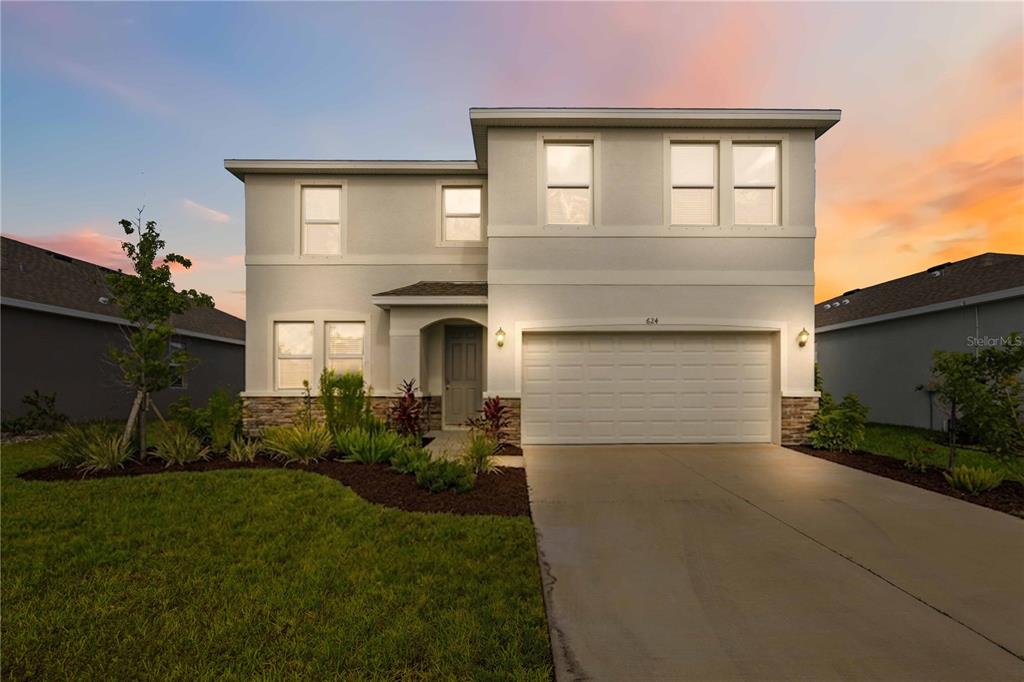 A two-story suburban house with a white stucco facade, stone accents, and a two-car garage — 624 160TH STREET E, BRADENTON, FL