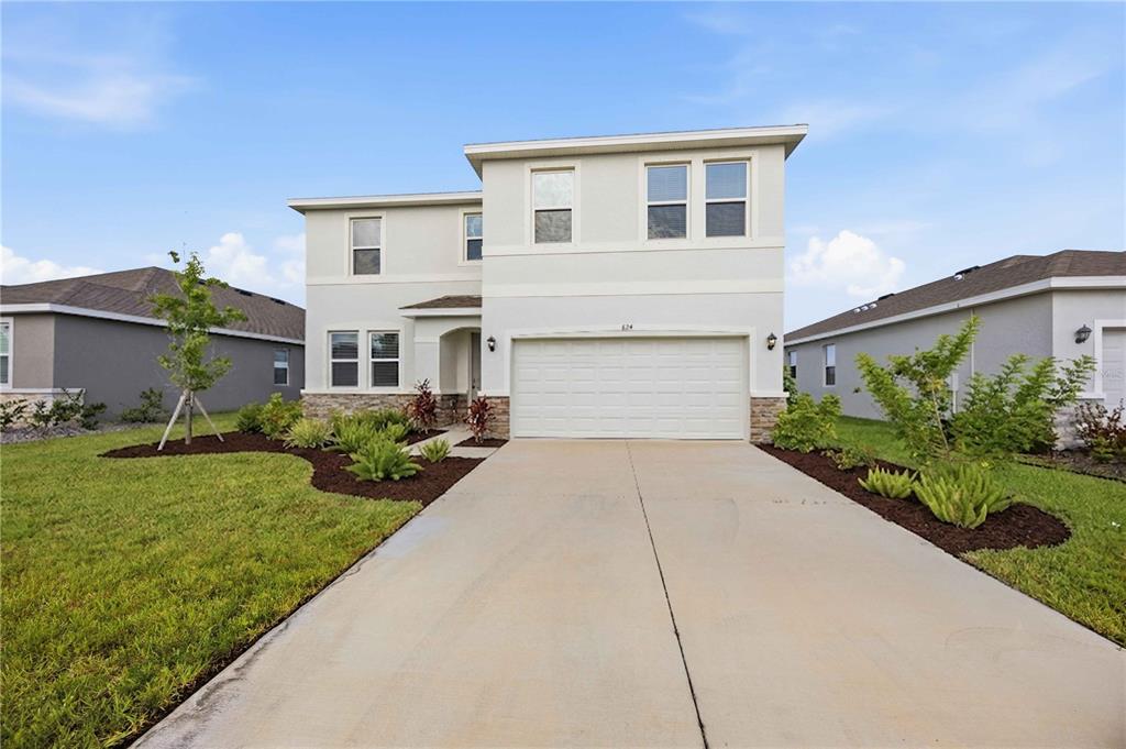 A two-story suburban house with a light-colored facade, a two-car garage, and landscaped front yard — 624 160TH STREET E, BRADENTON, FL