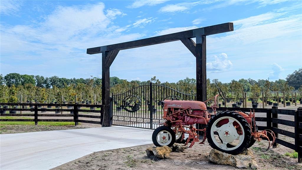 A vintage red tractor sits in front of a gated entrance with a wooden archway — 610 N HOLLANDTOWN ROAD, WAUCHULA, FL