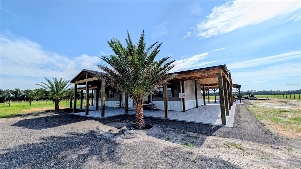 A single-story house features a large covered patio with wooden posts and a palm tree — 610 N HOLLANDTOWN ROAD, WAUCHULA, FL