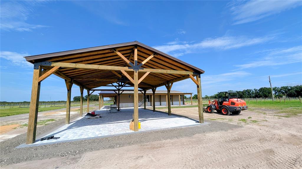 A large, open-air wooden pavilion with a paver floor stands next to a house — 610 N HOLLANDTOWN ROAD, WAUCHULA, FL