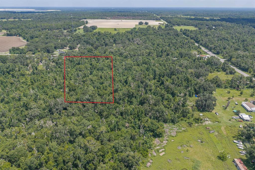 An aerial view shows a rectangular plot of land outlined in red amidst dense forest — 18525 672 HIGHWAY, LITHIA, FL