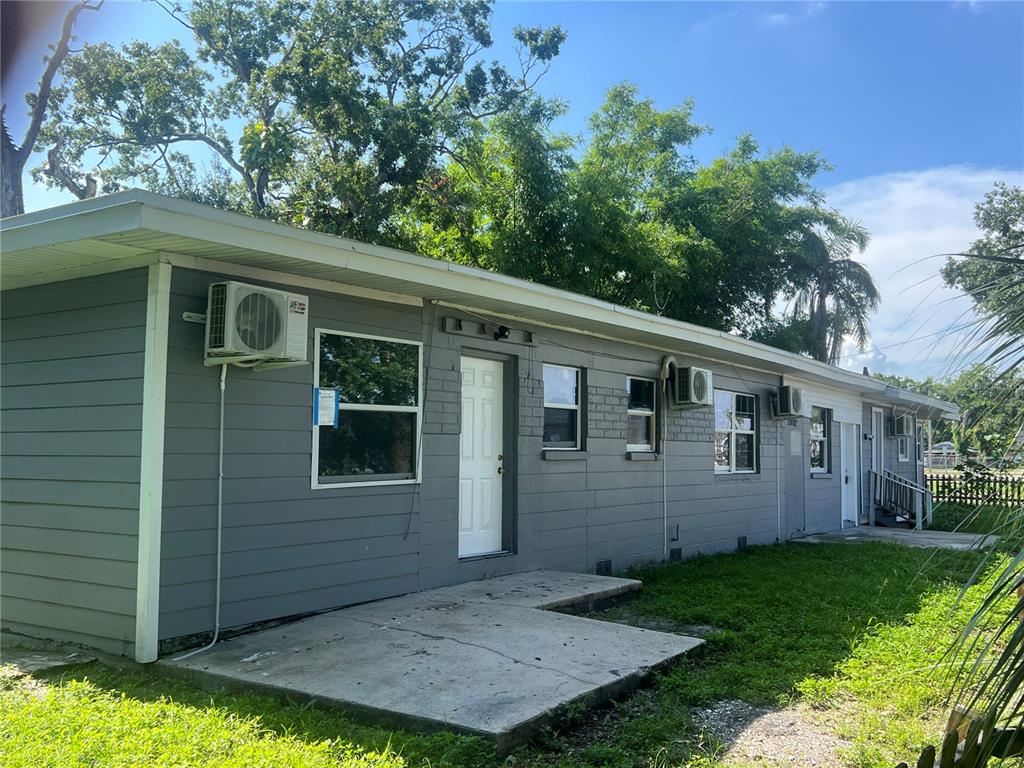 The exterior of a gray, single-story building features multiple window air conditioning units and concrete patios — 2002 E 33RD AVENUE, TAMPA, FL