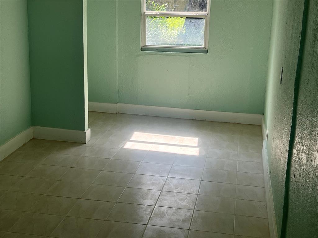 A small room with light green walls, white baseboards, and light-colored square floor tiles — 2002 E 33RD AVENUE, TAMPA, FL