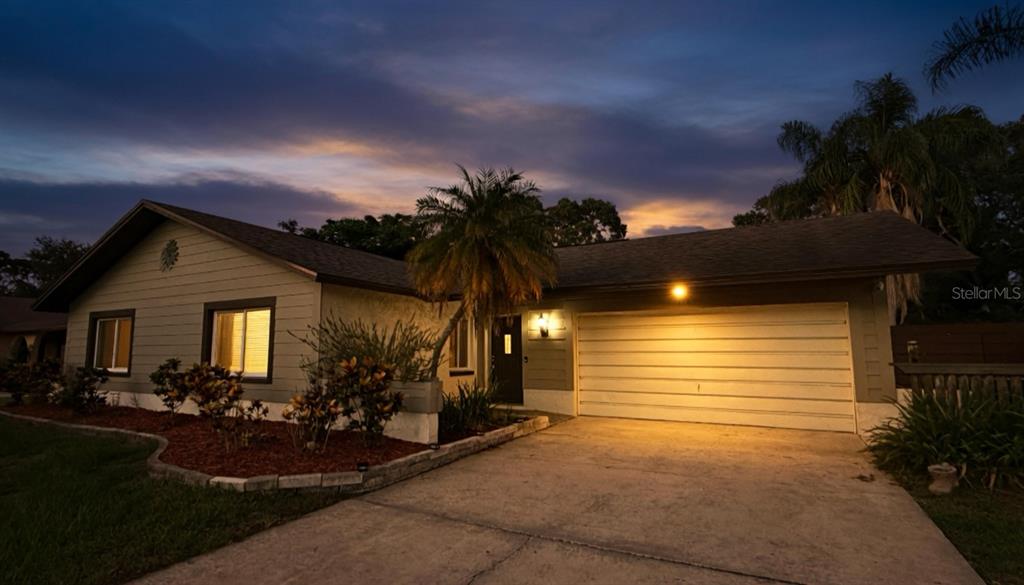 A small paved patio is enclosed by a horizontal wood privacy fence and lush greenery — 1583 REDWOOD AVENUE, DUNEDIN, FL