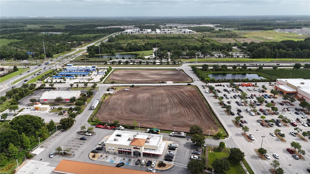 An aerial view shows a Wawa store, parking lots, and two cleared, undeveloped land parcels — 5092 OLD TAMPA HWY UNIT 01, KISSIMMEE, FL