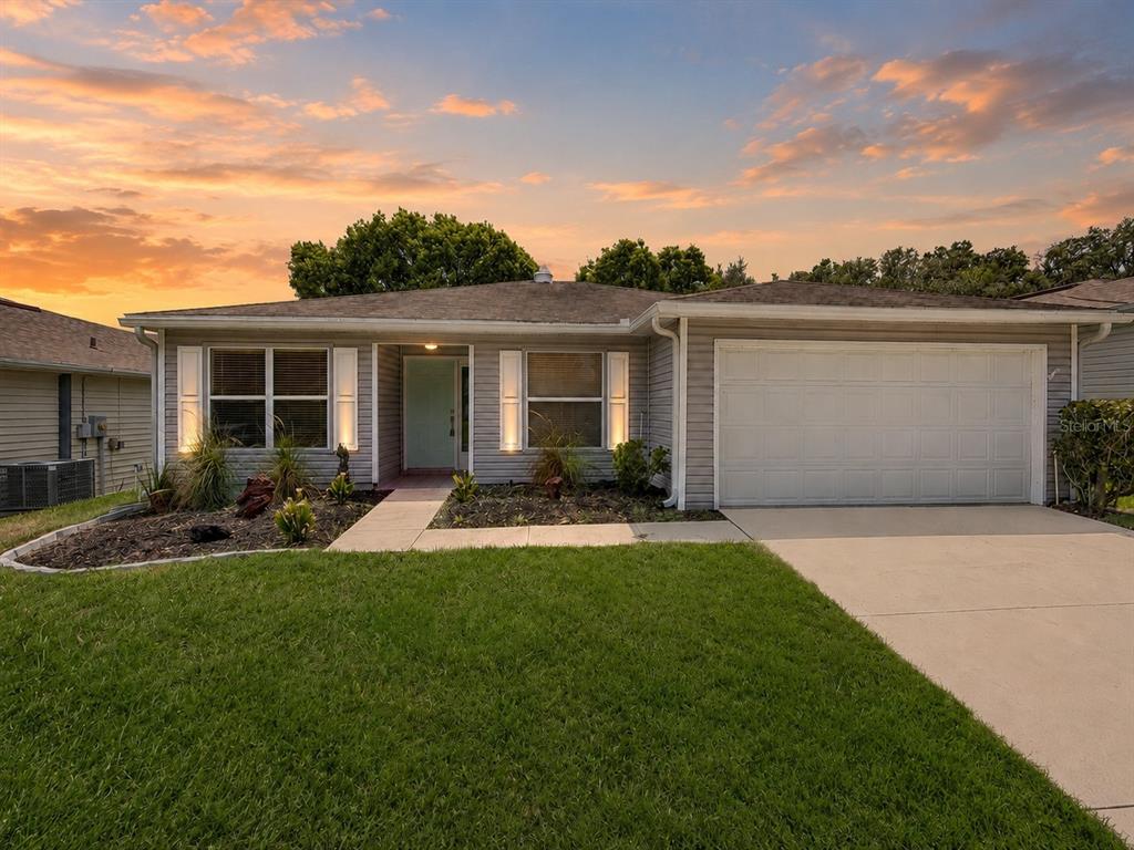 A single-story house with gray siding, a white garage door, and a front lawn — 29204 PRINCEVILLE DRIVE, SAN ANTONIO, FL