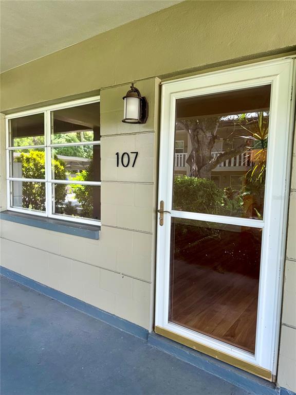 The exterior view shows a beige concrete block wall with a window, door, and light — 450 32ND AVE N UNIT 107W, ST PETERSBURG, FL