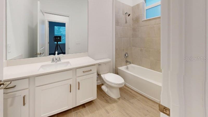 A bathroom features a white vanity, a toilet, and a tiled shower-tub combination — 7761 LAKES EDGE LANE, PORT CHARLOTTE, FL