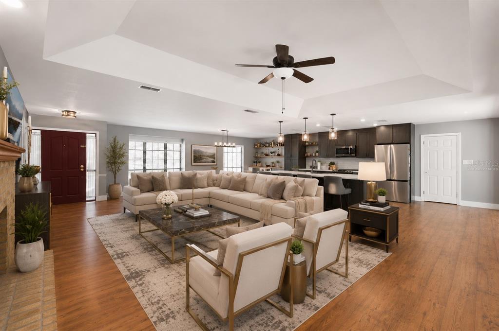 A spacious open-concept living room features a large sectional, kitchen island, and hardwood flooring — 432 BURNT TREE LANE, APOPKA, FL