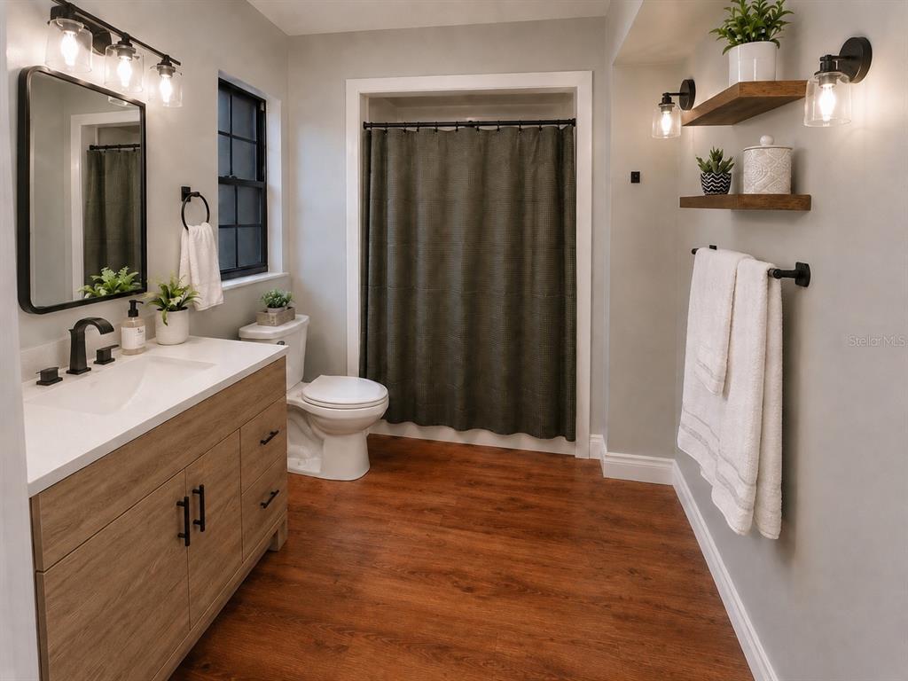 A bathroom features a wood vanity, white countertop, dark shower curtain, and wall-mounted wooden shelves — 432 BURNT TREE LANE, APOPKA, FL