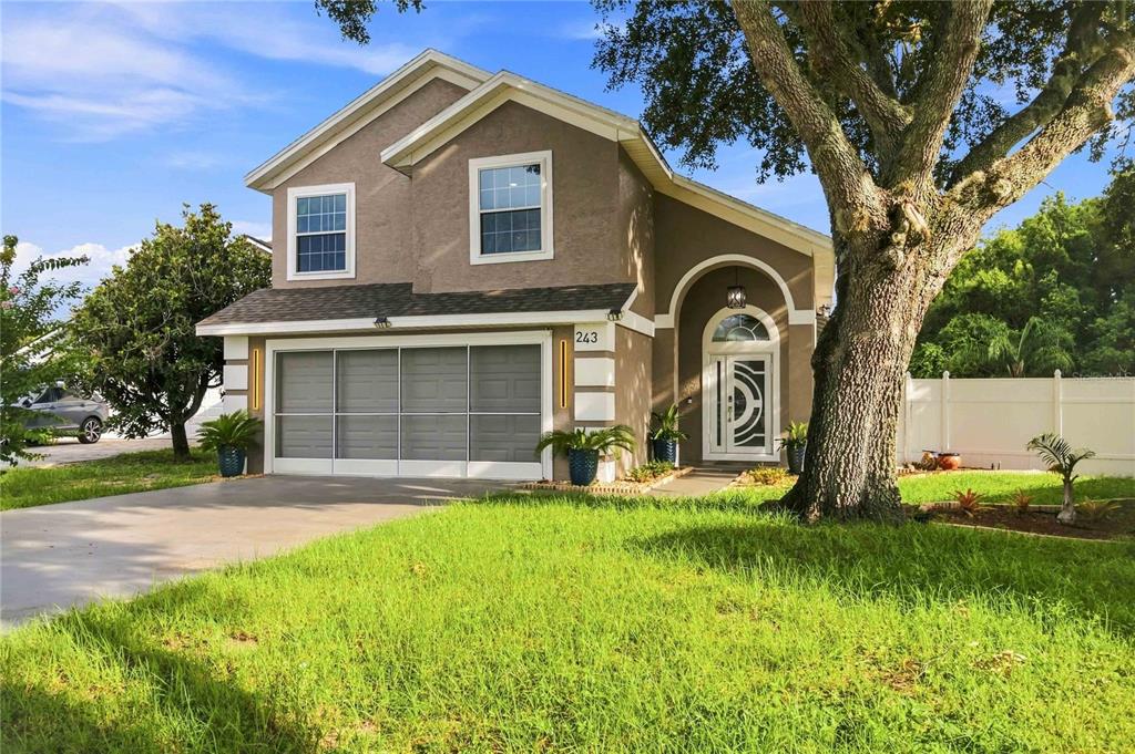 A two-story house with a garage, a front door with a decorative arch, and a tree — 243 OXFORD ROAD, DAVENPORT, FL