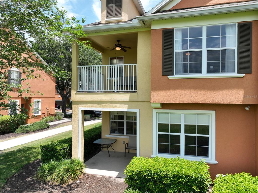 A two-story building exterior features a covered ground-floor patio and an upper-level balcony — 7586 ASSEMBLY LANE, REUNION, FL