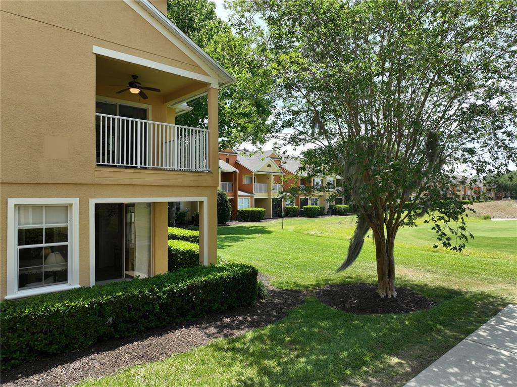 A two-story building exterior features a ground-level patio and an upper-level balcony with a fan — 7586 ASSEMBLY LANE, REUNION, FL