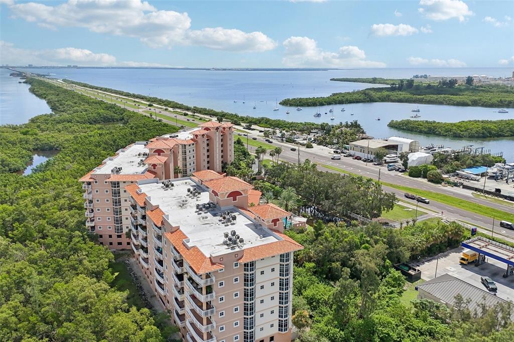 An aerial view shows a multi-story residential building surrounded by dense trees near a highway — 12033 GANDY BOULEVARD N UNIT 145, ST PETERSBURG, FL