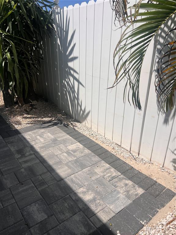 A paved walkway with a dark border runs between a house and a white fence — 40 82ND AVENUE Unit 3, ST PETERSBURG, FL