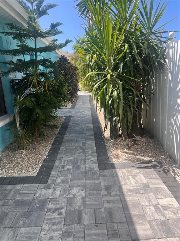 A paved walkway runs alongside a blue house exterior and a white privacy fence — 40 82ND AVENUE Unit 3, ST PETERSBURG, FL
