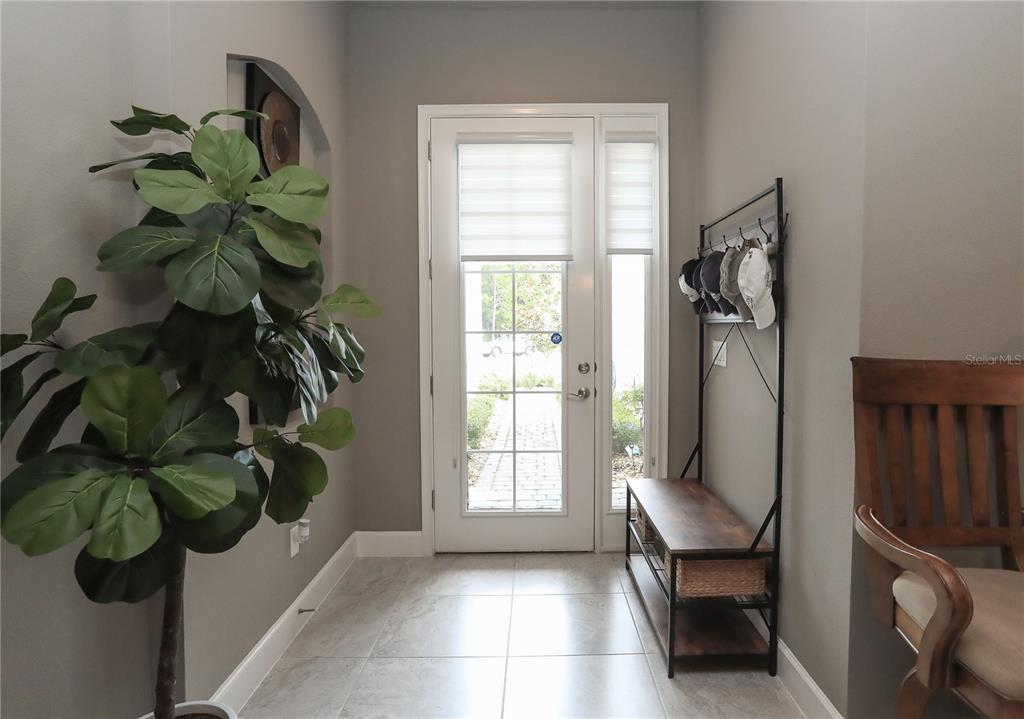 An entryway features a front door, a potted plant, a coat rack, and tile flooring — 875 PINEWOOD DRIVE, ORMOND BEACH, FL