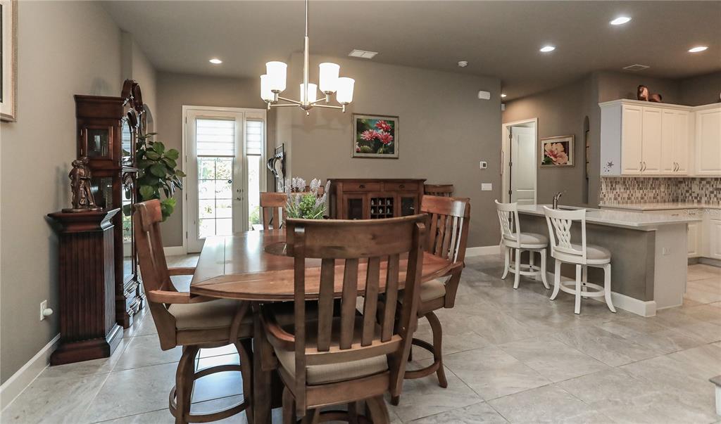 A dining area with a wooden table and chairs sits adjacent to a kitchen island — 875 PINEWOOD DRIVE, ORMOND BEACH, FL