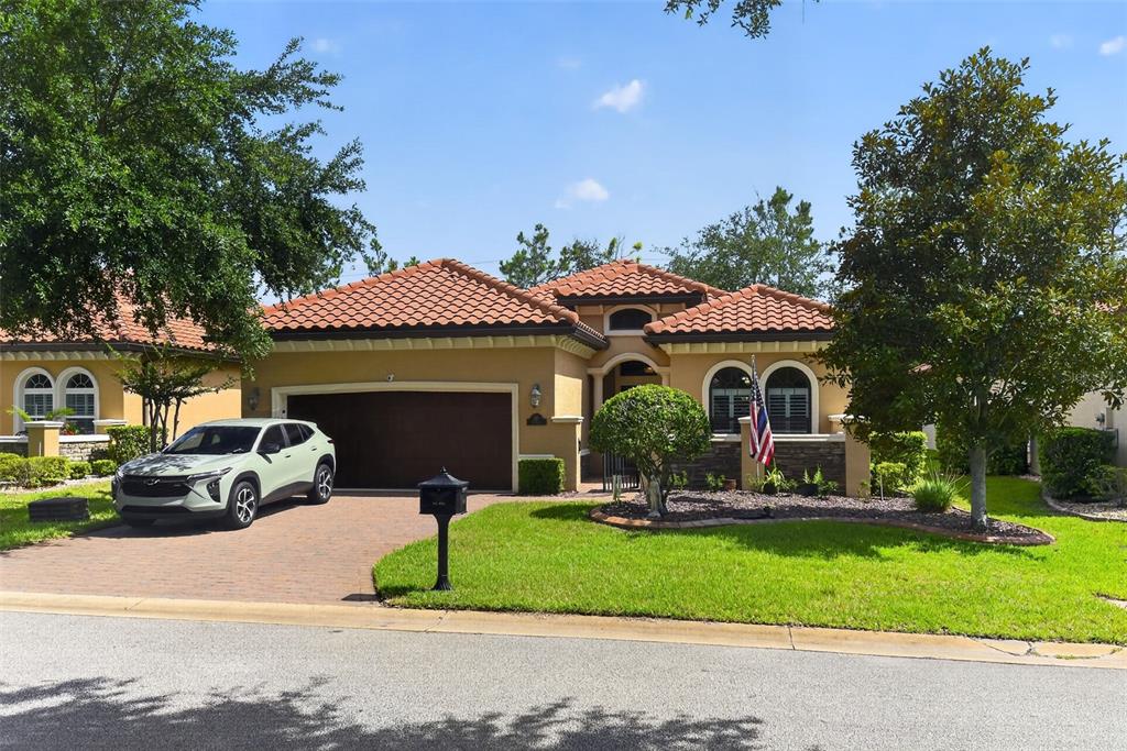 A single-story house with a tile roof, two-car garage, and a paved driveway — 110 VIA ROMA, ORMOND BEACH, FL