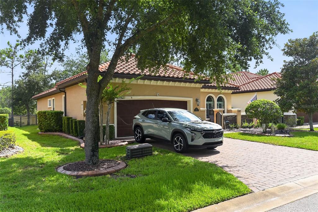 A light-colored SUV is parked in the driveway of a single-story house with tile roofing — 110 VIA ROMA, ORMOND BEACH, FL