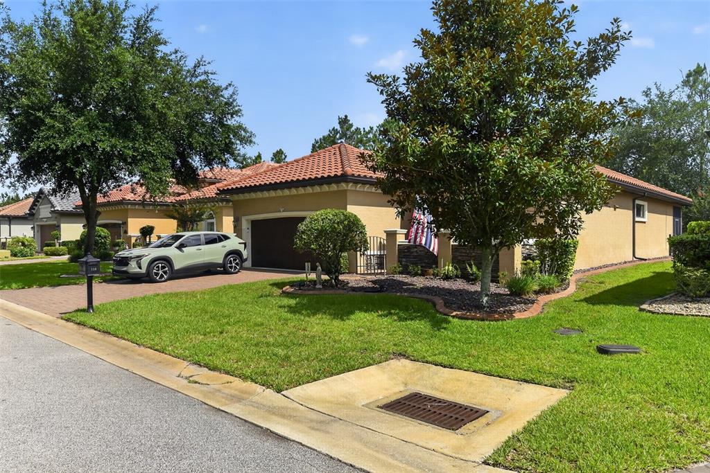 A single-story house with a tile roof, tan stucco exterior, and a paved driveway — 110 VIA ROMA, ORMOND BEACH, FL