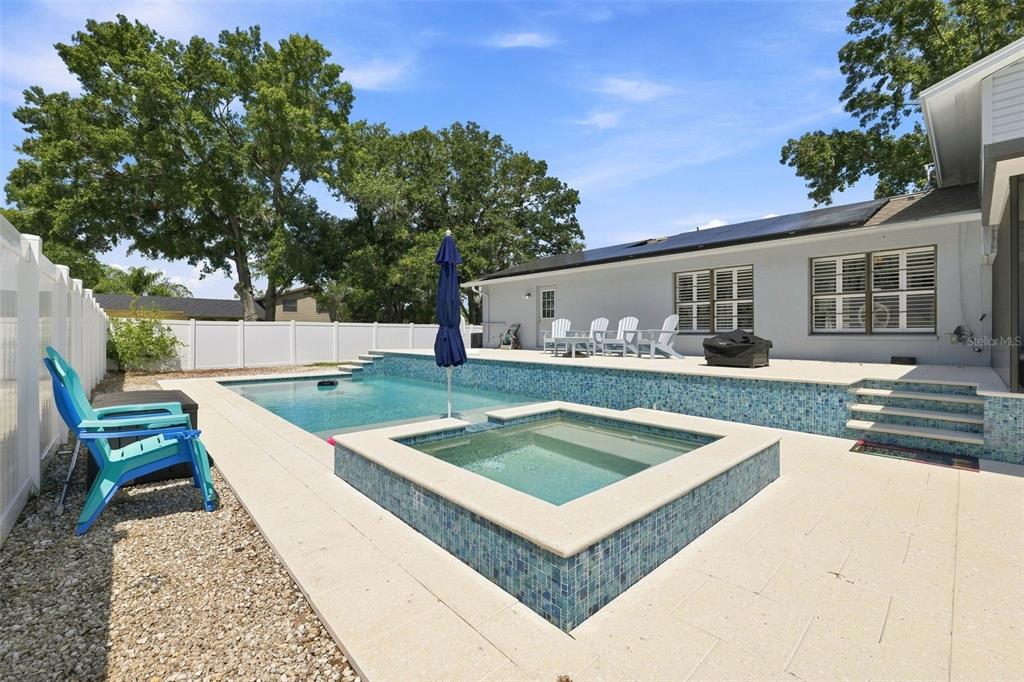 A backyard features a swimming pool, a raised spa, and a patio with outdoor seating — 15868 COUNTRY LAKE DRIVE, TAMPA, FL