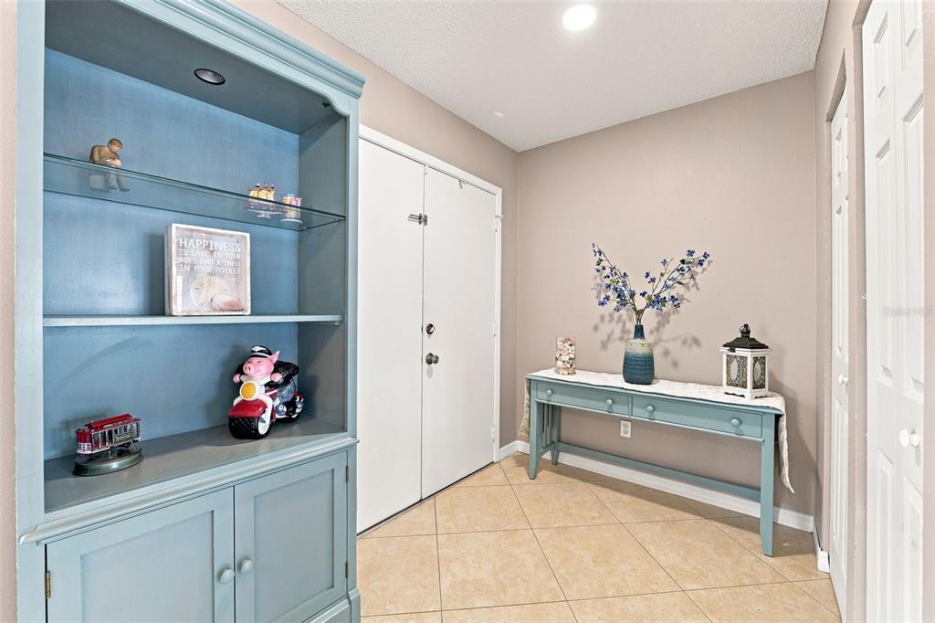 An entryway features a blue built-in bookshelf, a matching console table, and tile flooring — 15868 COUNTRY LAKE DRIVE, TAMPA, FL