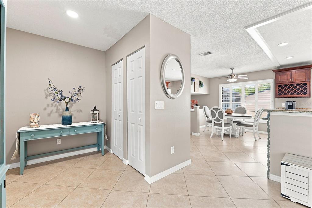 A foyer with a blue console table leads to a dining area with tiled floors — 15868 COUNTRY LAKE DRIVE, TAMPA, FL