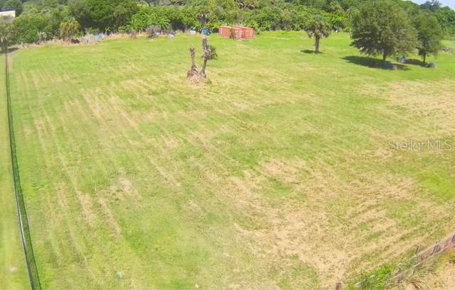 An aerial view of a large, grassy, fenced-in vacant lot with a few scattered trees — 3832 SERENITY LANE, MIMS, FL