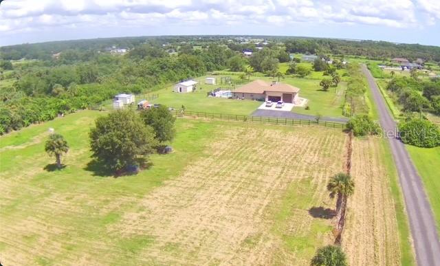 An aerial view shows a house with a pool and outbuildings on a large grassy lot — 3832 SERENITY LANE, MIMS, FL