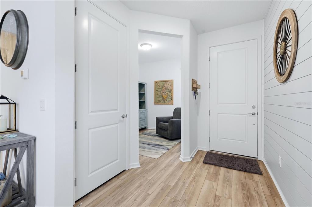 An entryway features light wood-look flooring, shiplap wall accents, and a white door — 9289 BALLASTER POINTE LOOP, PARRISH, FL