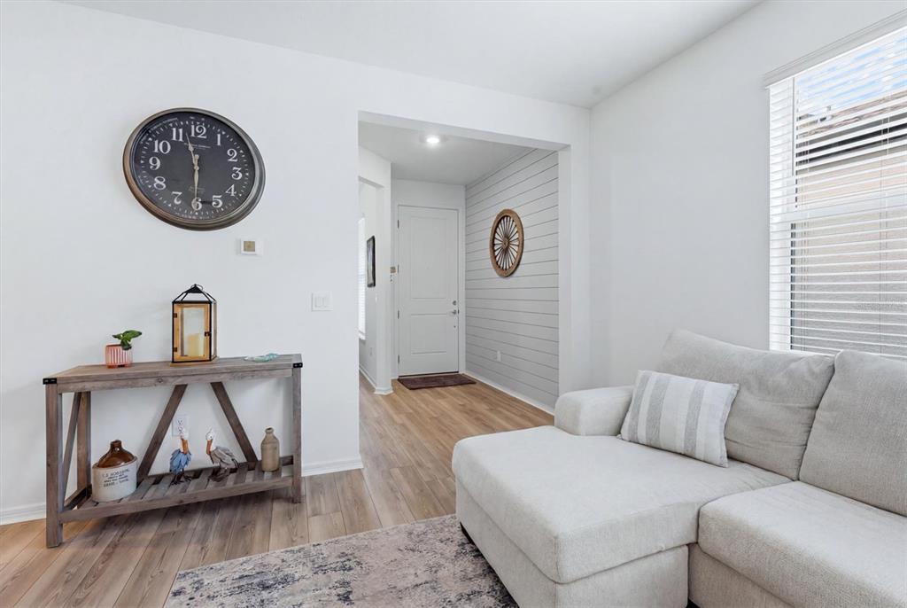A living room features a sectional sofa, a console table, and a shiplap entryway wall — 9289 BALLASTER POINTE LOOP, PARRISH, FL
