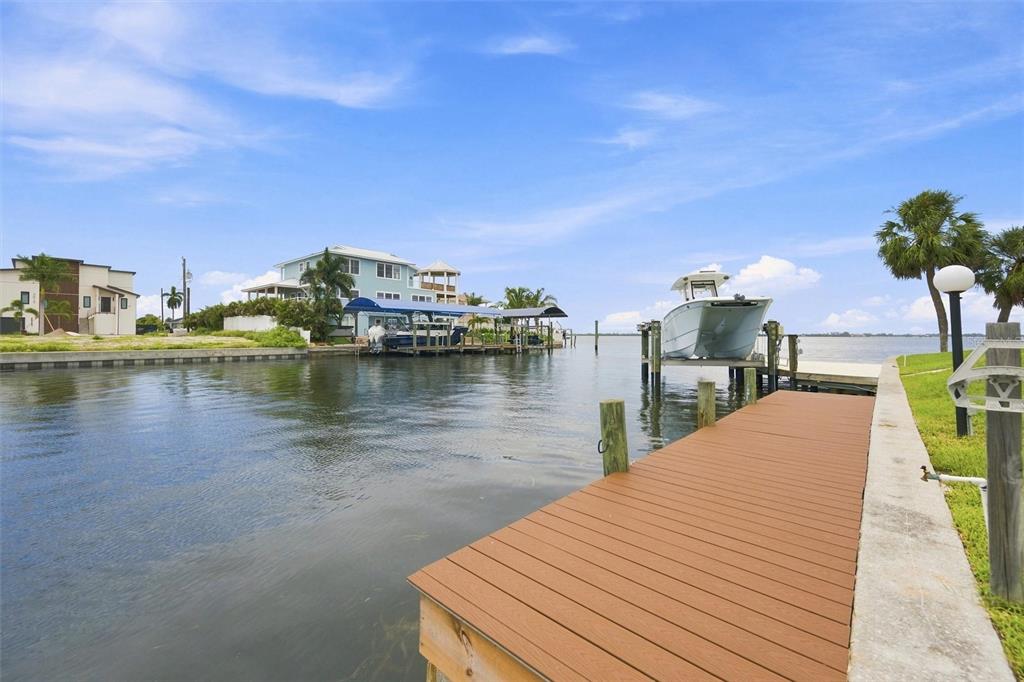 A wooden dock extends into a canal toward a boat lift and waterfront houses — 3840 CATALINA DRIVE, BRADENTON, FL