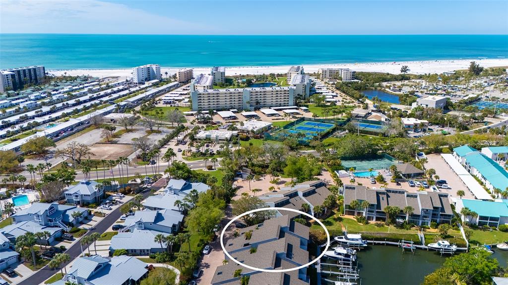 An aerial view shows a multi-story residential building with a gray roof near a canal — 1249 DOCKSIDE PLACE UNIT 110, SARASOTA, FL