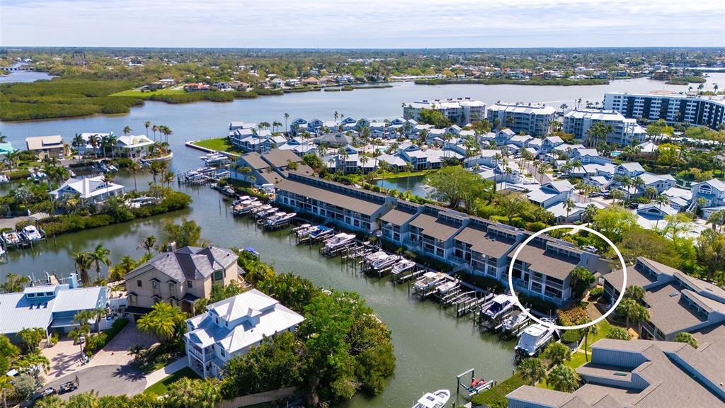 An aerial view shows a waterfront townhouse complex with boat slips and a circled unit — 1249 DOCKSIDE PLACE UNIT 110, SARASOTA, FL