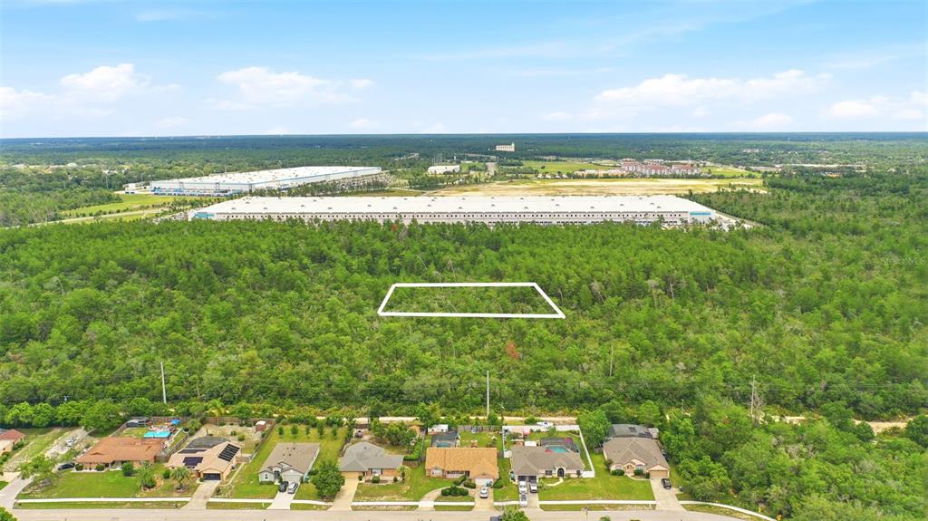 An aerial view shows a rectangular plot of land outlined in white amidst a wooded area — WOLVERINE (PAPER) AVENUE, DELTONA, FL