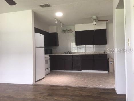 A kitchen features dark cabinets, white appliances, and light-colored tile flooring — 22201 SW BEACH BOULEVARD, DUNNELLON, FL