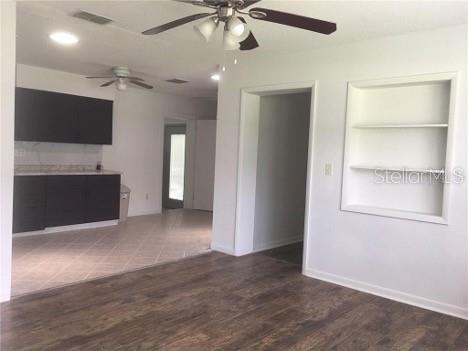 A room with dark kitchen cabinets, wood-look flooring, a ceiling fan, and built-in wall shelves — 22201 SW BEACH BOULEVARD, DUNNELLON, FL