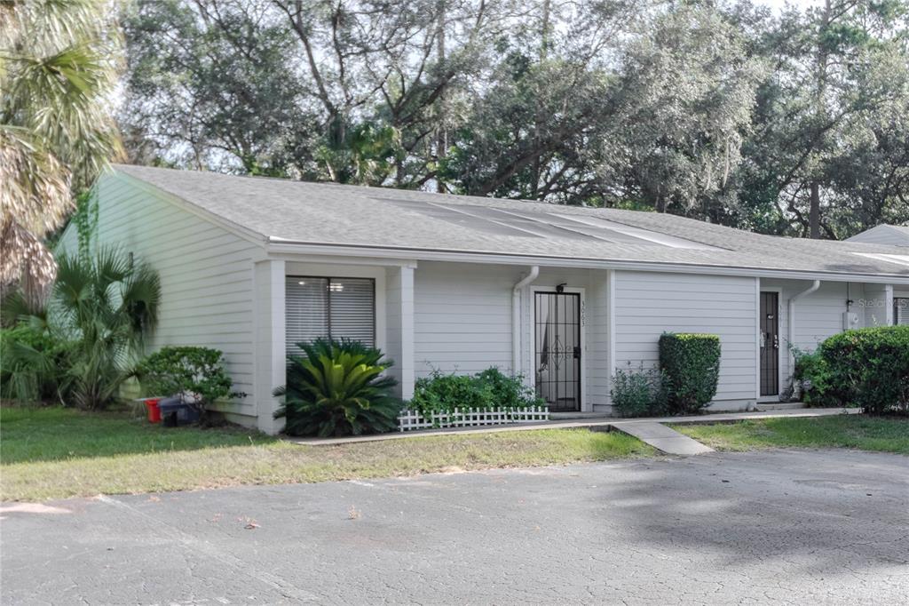 A single-story residential building with light-colored siding, a shingled roof, and a paved parking area — 3063 NW 28TH CIRCLE UNIT 3063, GAINESVILLE, FL