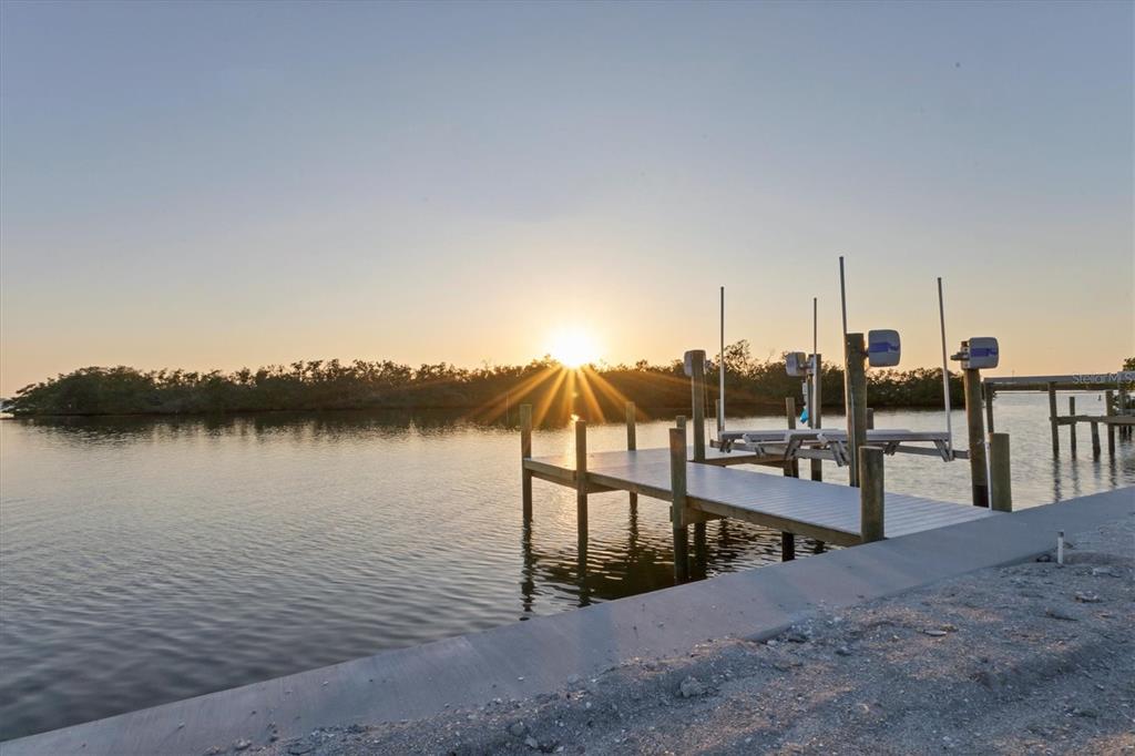 A wooden dock extends into a calm waterway at sunset with a mangrove island beyond — 7314 WESTMORELAND DRIVE, SARASOTA, FL