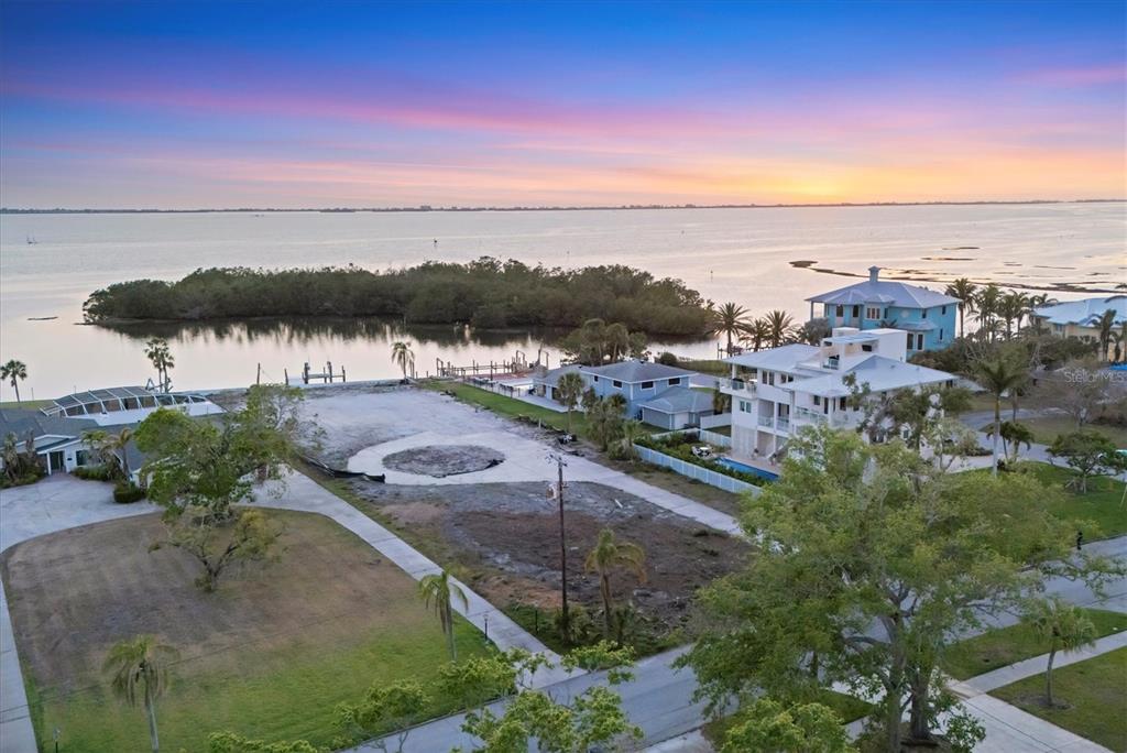 An aerial view shows a cleared waterfront lot situated between two houses at sunset — 7314 WESTMORELAND DRIVE, SARASOTA, FL