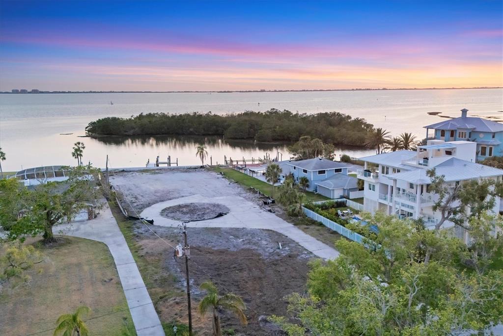 An aerial view shows a vacant waterfront lot with a circular concrete pad at sunset — 7314 WESTMORELAND DRIVE, SARASOTA, FL