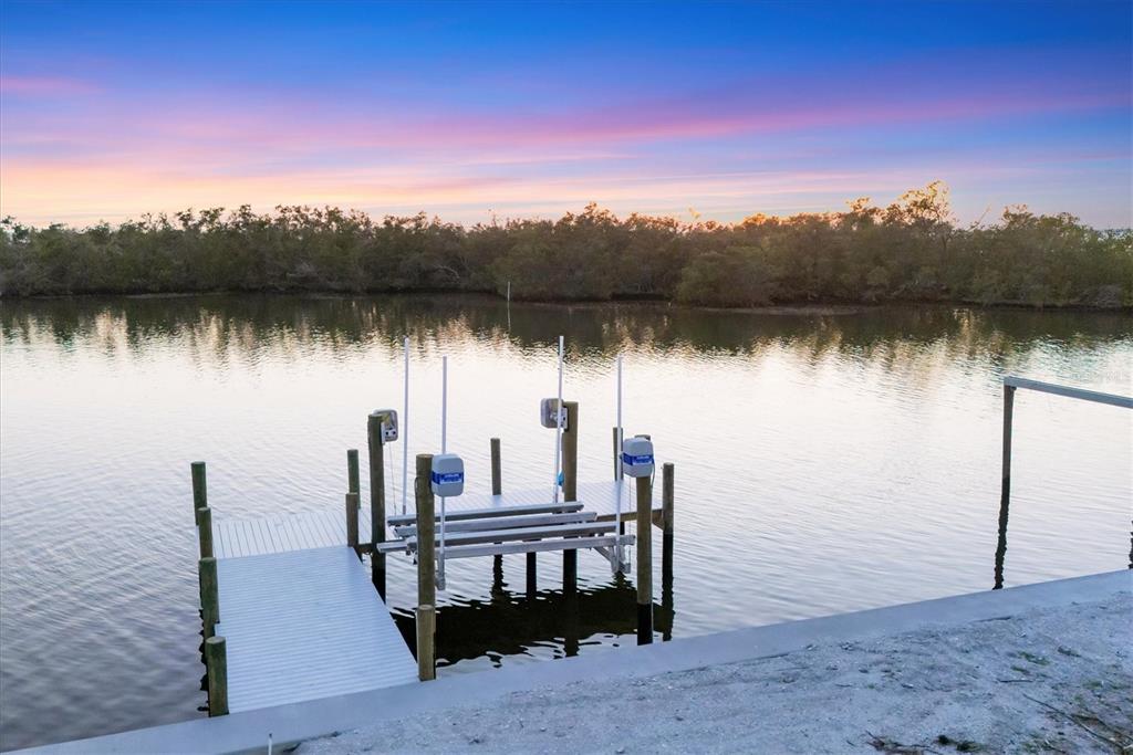 A boat lift sits at the end of a dock extending into a calm waterway — 7314 WESTMORELAND DRIVE, SARASOTA, FL