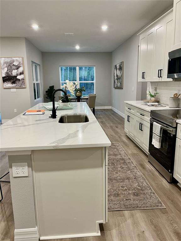 A kitchen features a white marble island, white cabinetry, stainless steel appliances, and wood flooring — 7 LOBELIA COURT, HOMOSASSA, FL