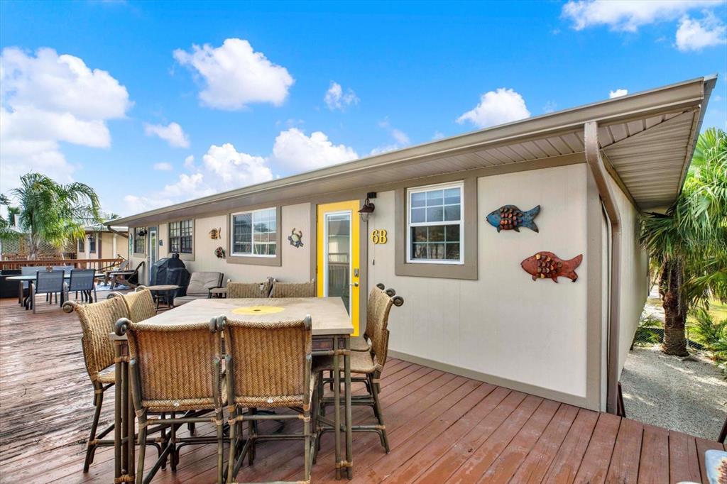 A wooden deck features a dining set in front of a building with a yellow door — 4909 GULF DRIVE UNIT 6B, HOLMES BEACH, FL