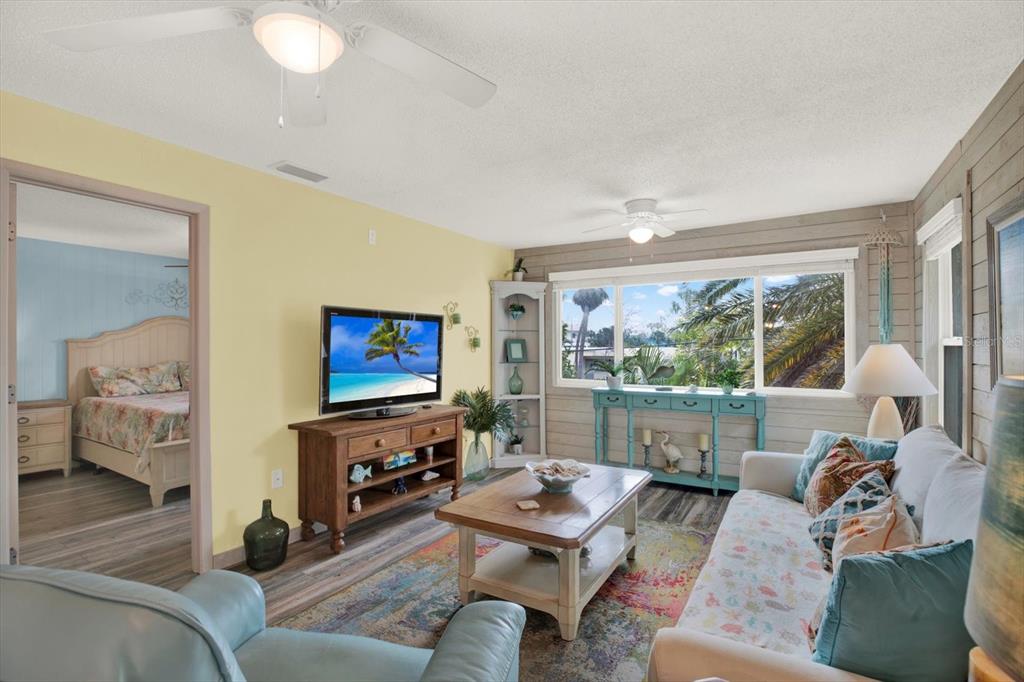A living room with a television, sofa, coffee table, and a view into a bedroom — 4909 GULF DRIVE UNIT 6B, HOLMES BEACH, FL