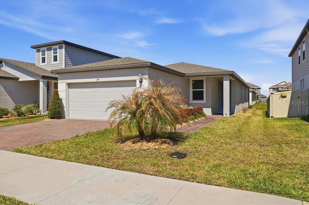 A single-story suburban house with a two-car garage and a paved driveway — 1799 CARNOSTIE ROAD, WINTER HAVEN, FL