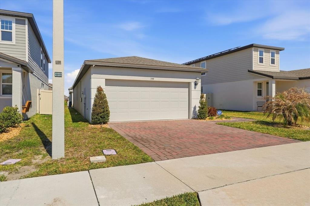 A single-story house with a brick driveway and a two-car garage — 1799 CARNOSTIE ROAD, WINTER HAVEN, FL